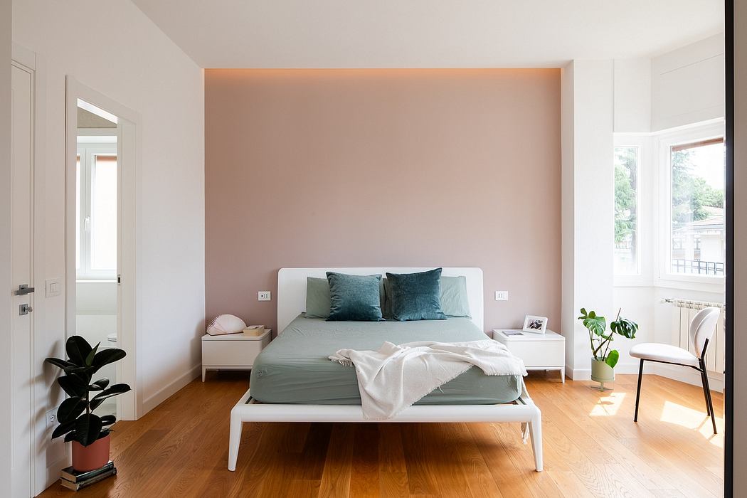 Spacious bedroom with white furniture, pastel walls, and large windows providing natural light.