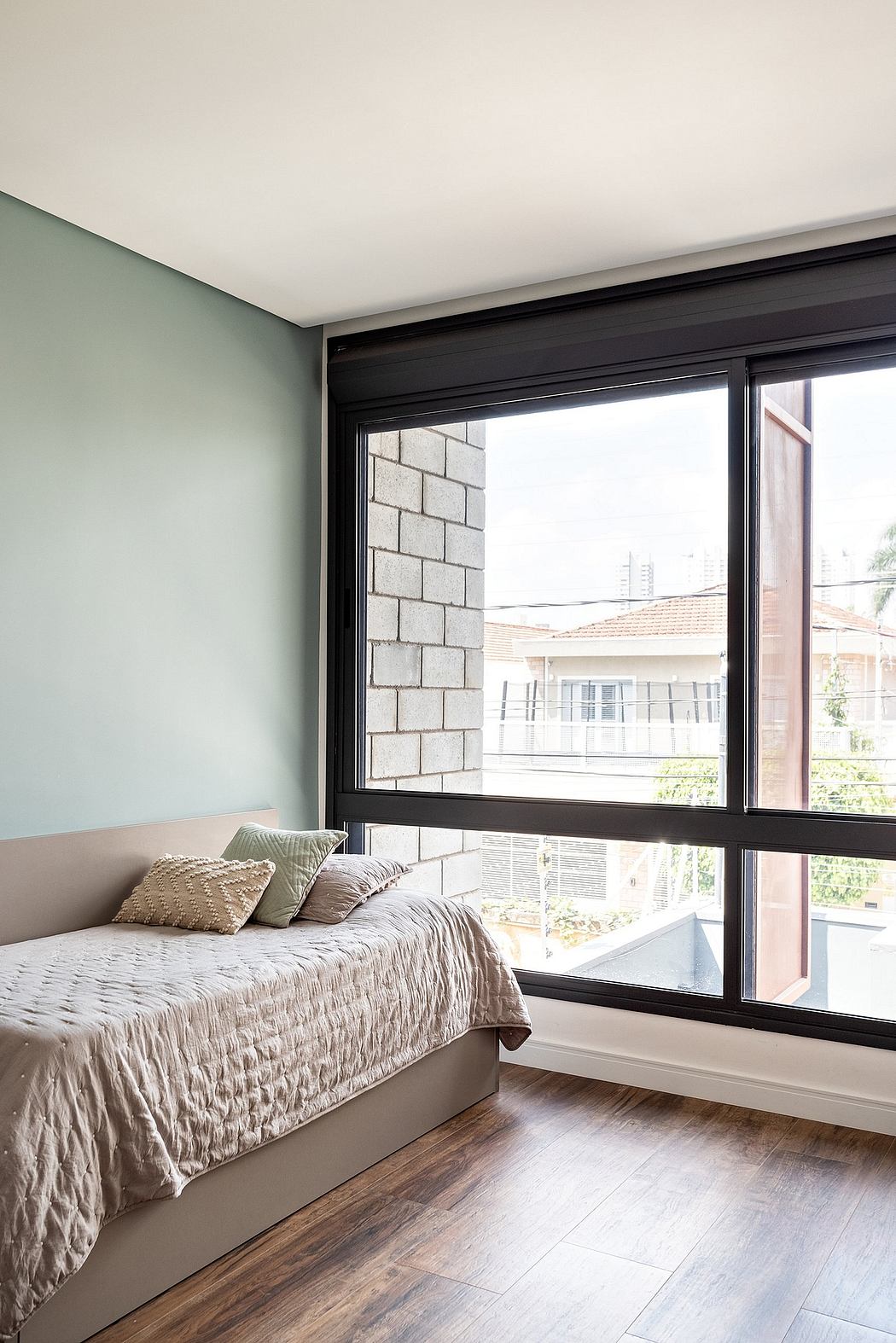 Minimalist bedroom with large windows, sleek black frames, and textured bedding.