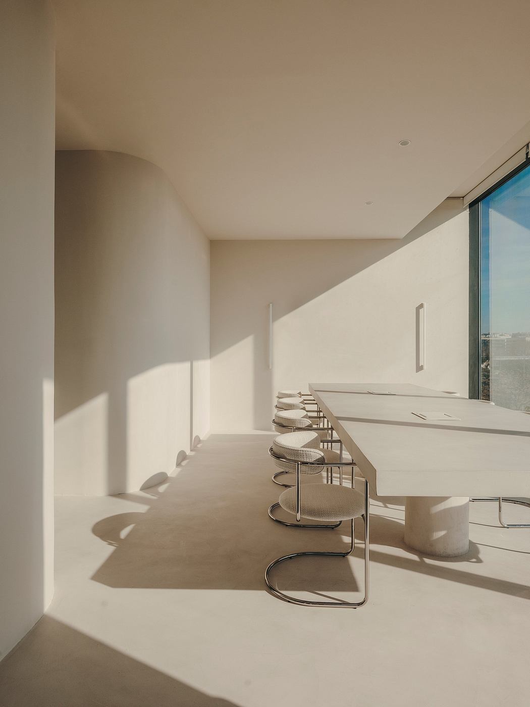 Minimalist dining area with sleek table, modern chairs, and large windows.