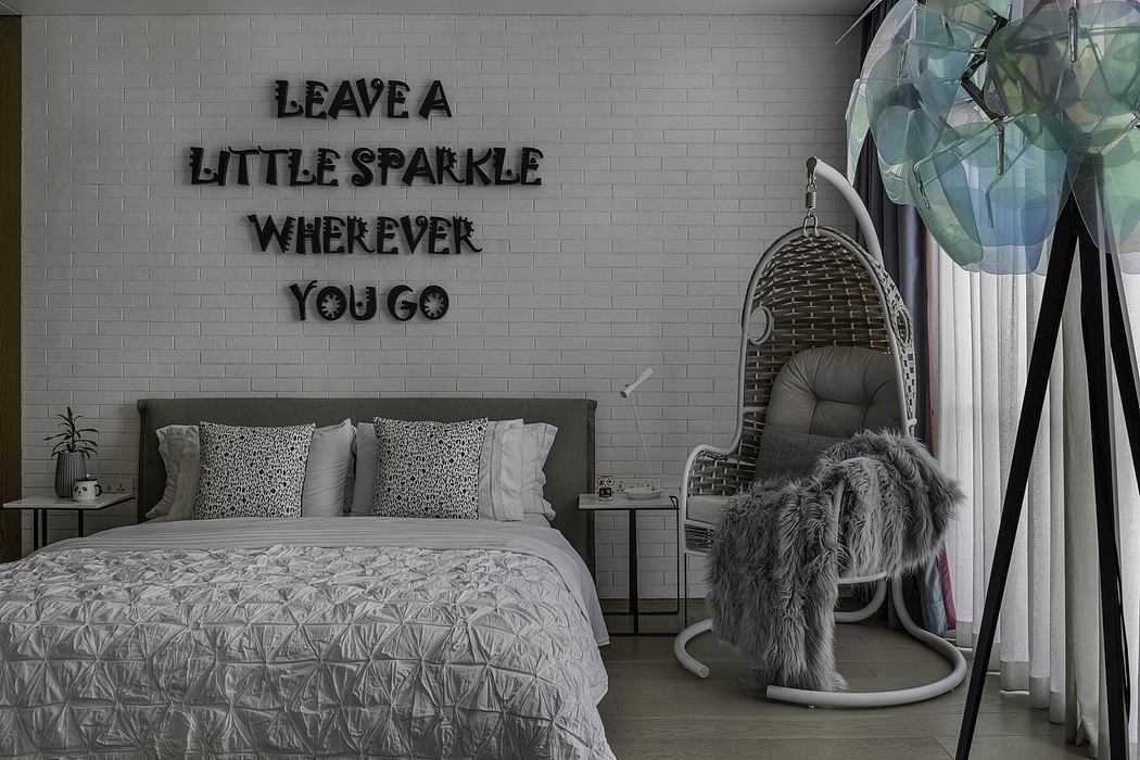 A cozy bedroom with a patterned bedspread, wicker chair, and motivational wall text.
