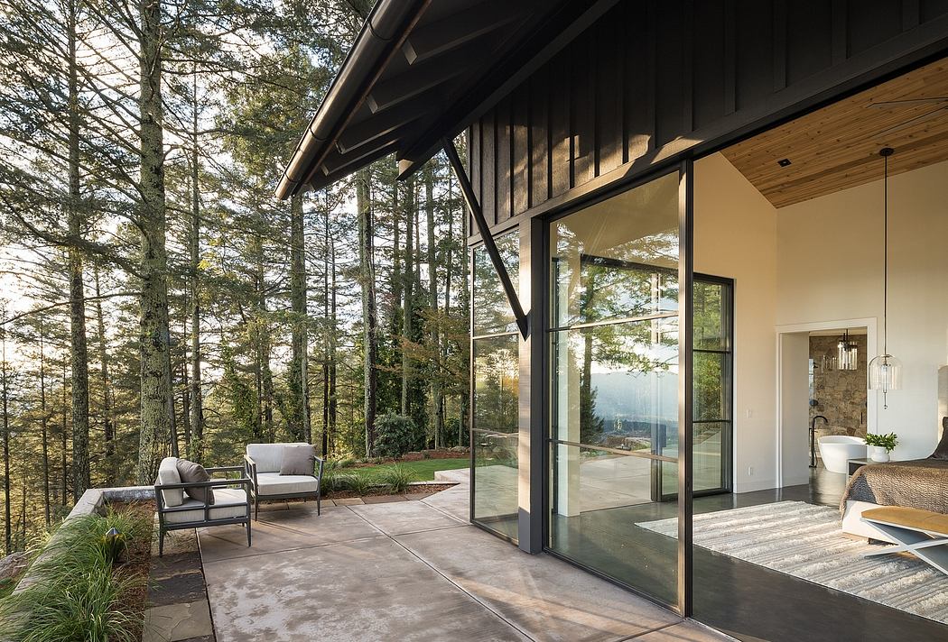 Modern mountain home with expansive glass walls overlooking lush forest landscape.
