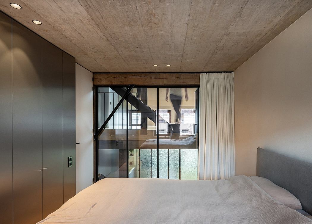 Concrete ceiling, wood and steel framing, curtains frame a glass wall with a person walking.