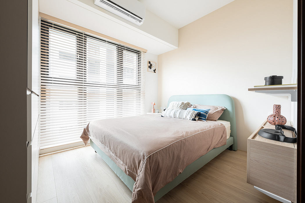 Minimalist bedroom with pastel-colored bedframe, built-in cabinetry, and large windows providing natural light.