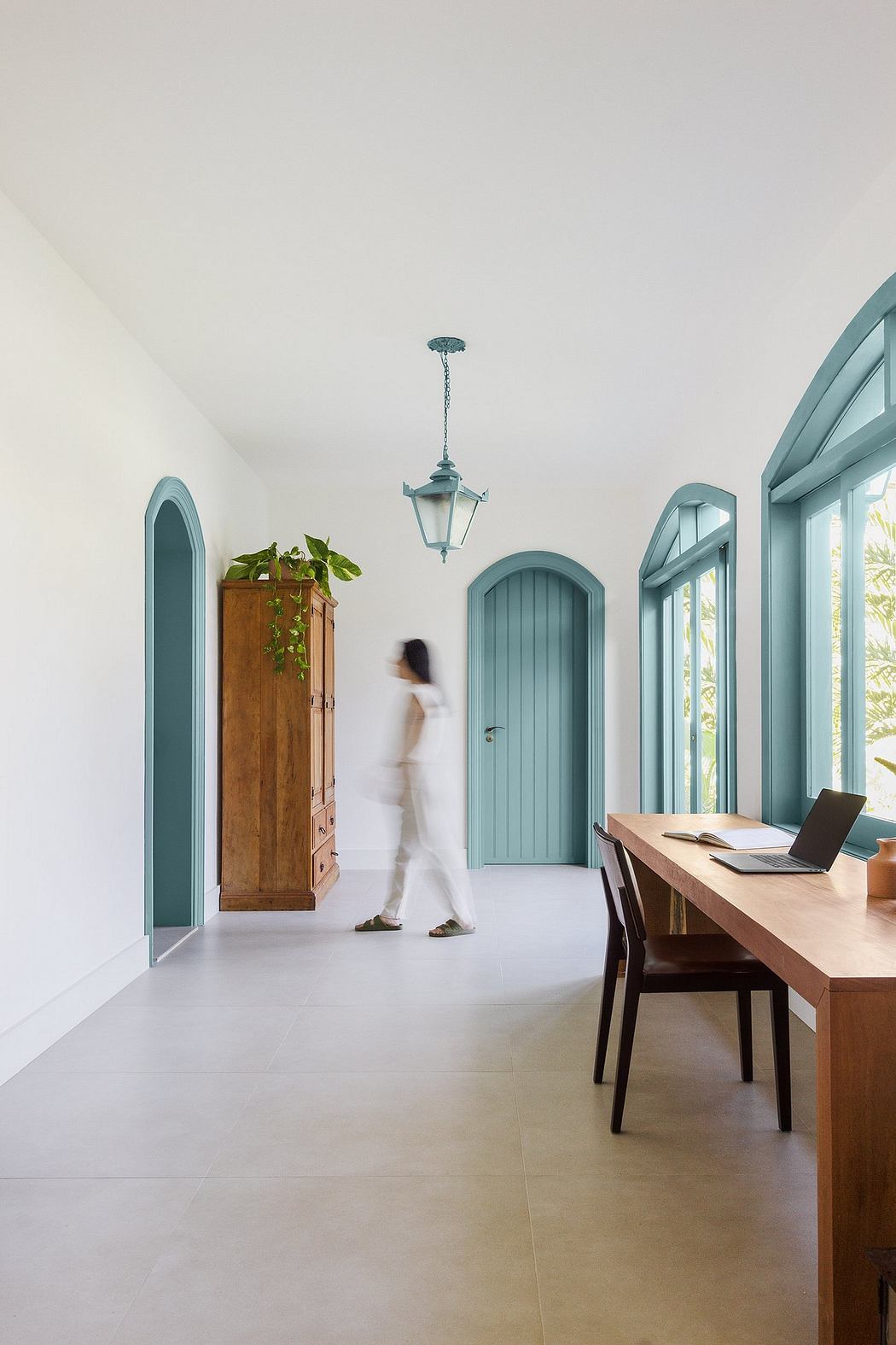 A bright, open space with arched doorways, wooden furnishings, and a hanging lantern.