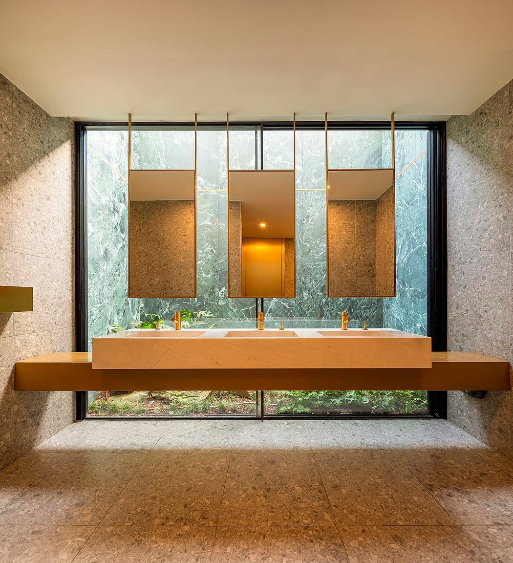 A modern bathroom with a large vanity, mirrored cabinets, and floor-to-ceiling windows overlooking nature.