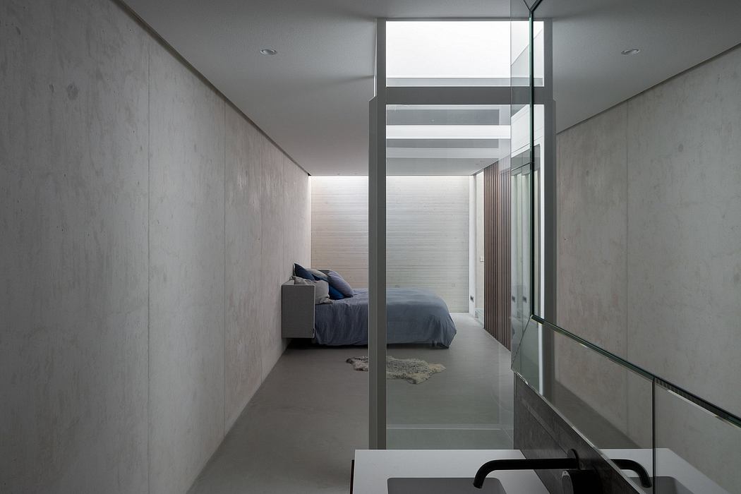 Minimalist concrete bedroom with glass partitions and recessed lighting. Sleek, modern design.