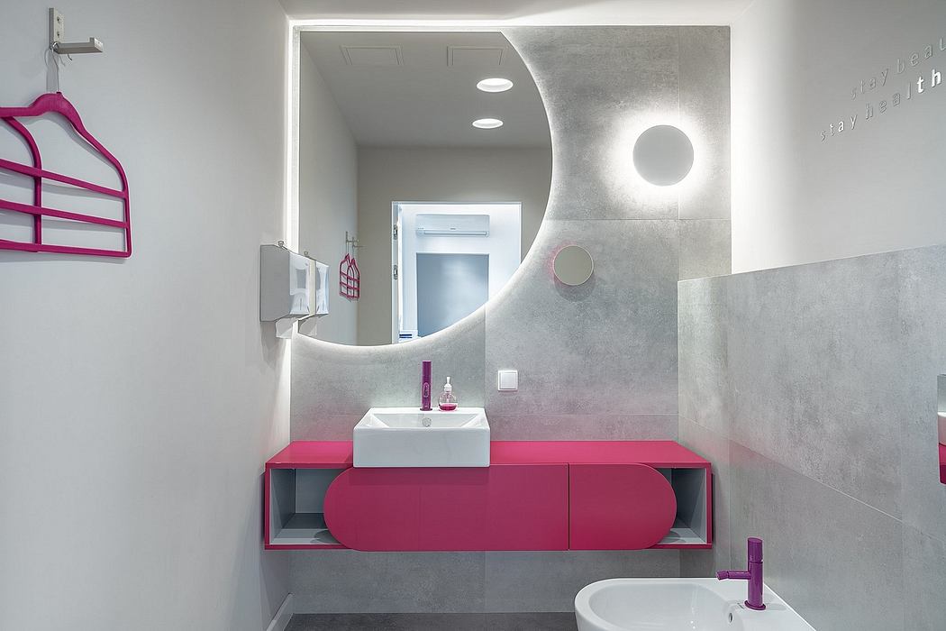 Sleek, modern bathroom with curved mirror, pink vanity, and minimalist lighting.