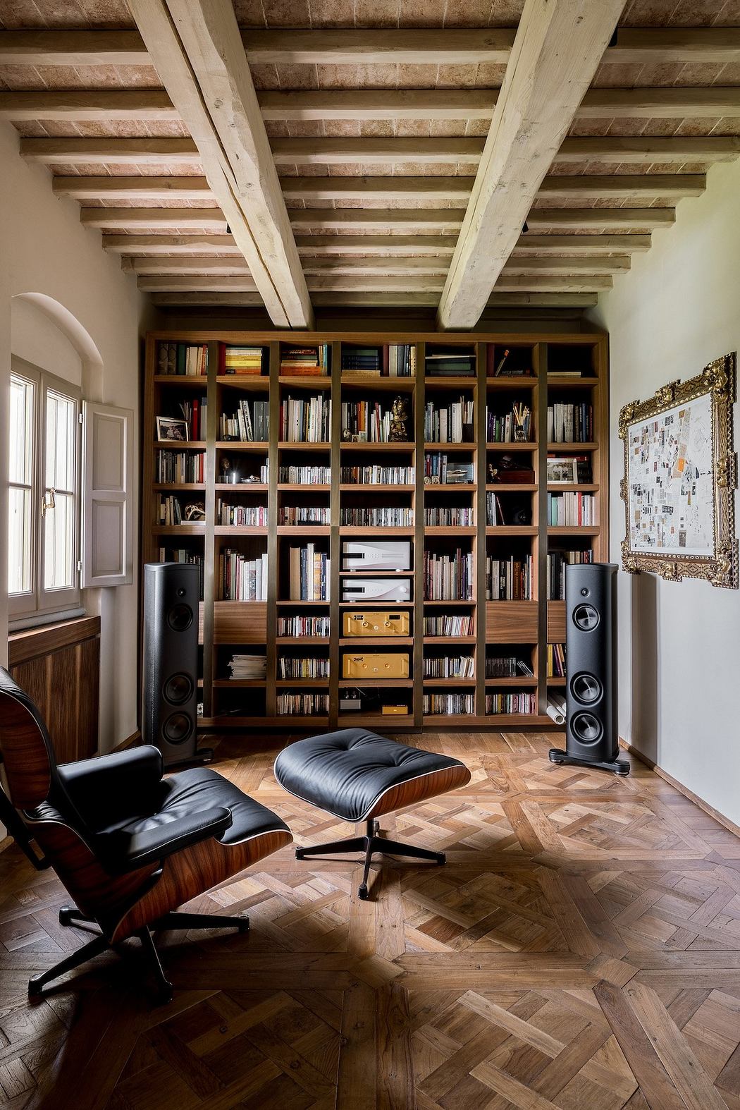 Wooden-beamed ceiling, floor-to-ceiling bookshelf, Eames chair, parquet flooring.