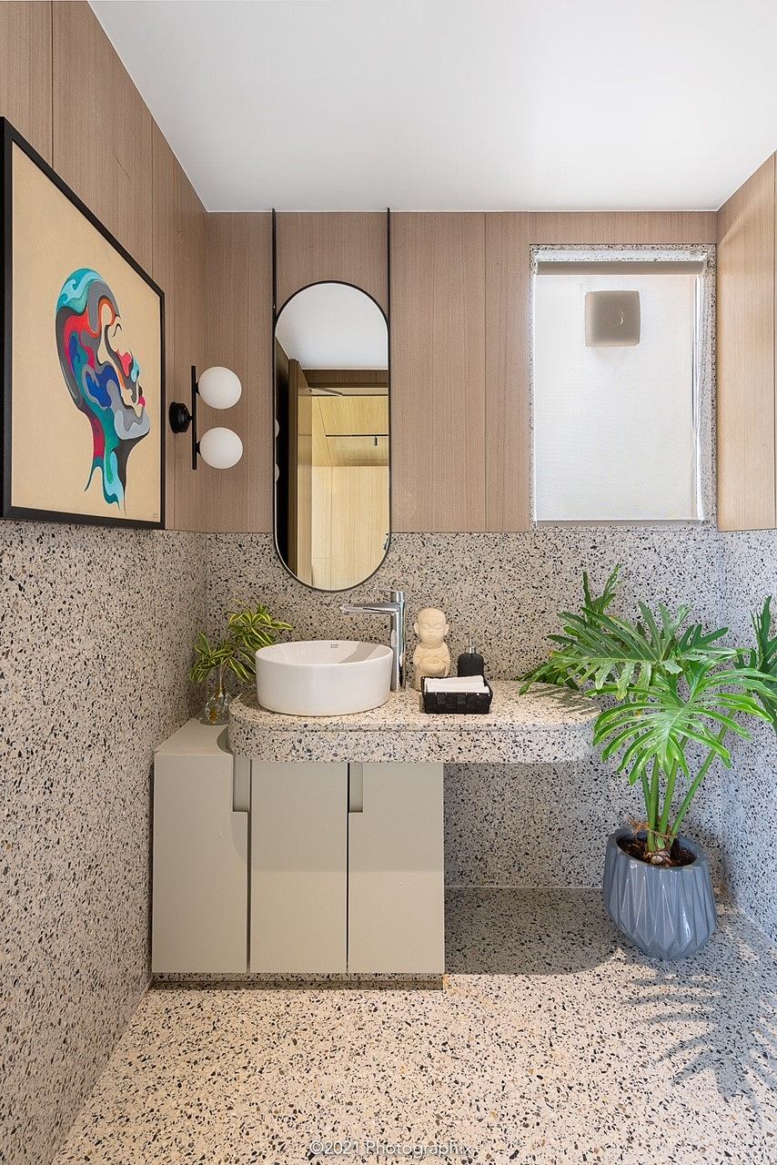 Well-designed modern bathroom with wooden walls, terrazzo countertop, and artful decor.
