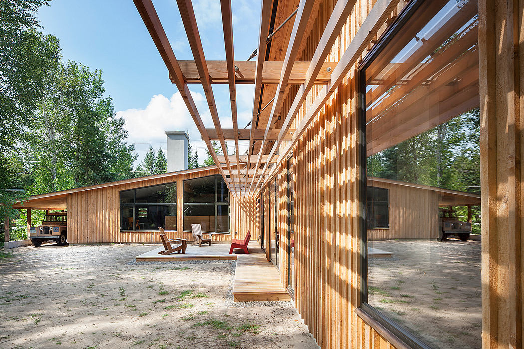 A modern wooden structure with large windows, beams, and an outdoor seating area.