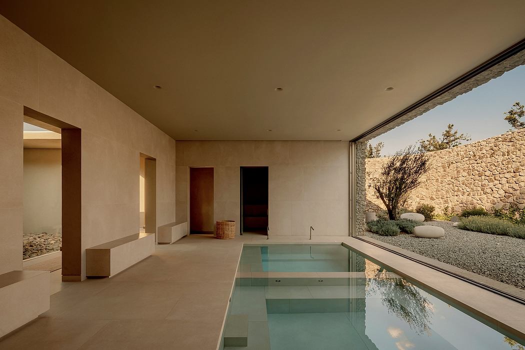 Sleek, modern indoor pool with minimalist stone wall, natural light, and lush landscaping.
