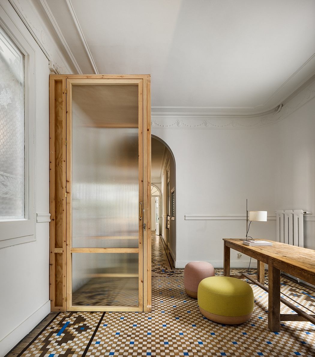 A wooden-framed glass door leads to a hallway with intricate tiled floors and modern furnishings.