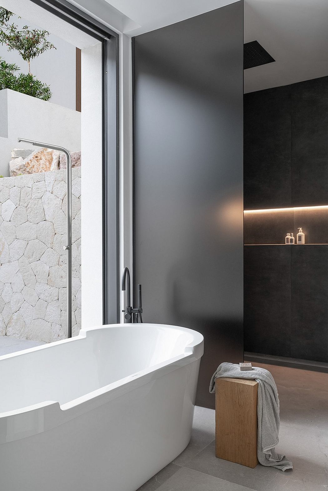 Sleek, minimalist bathroom with freestanding tub, black accent wall, and recessed lighting.