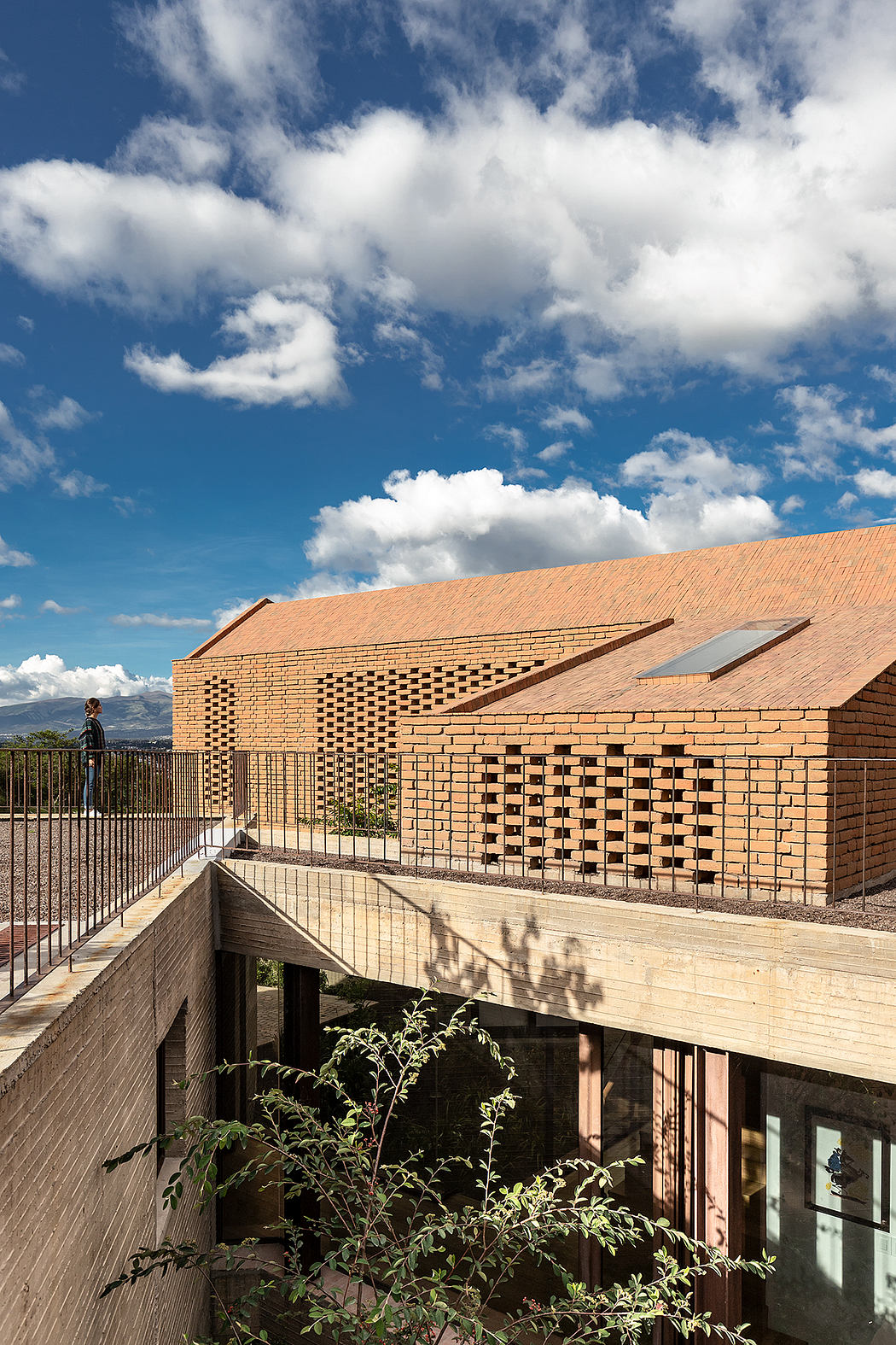 Striking brick facade with patterned brickwork and elevated walkway overlooking a scenic view.