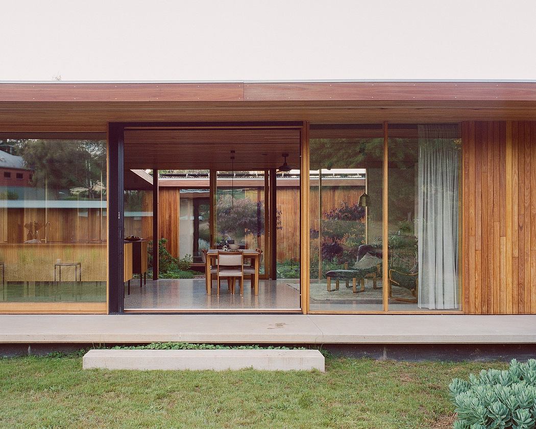 A modern, wooden structure with large glass panels overlooking a lush garden.