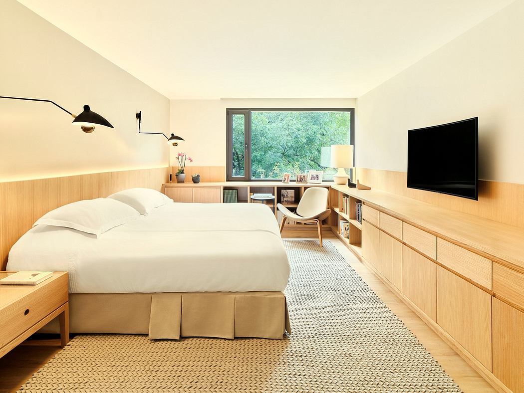 Spacious bedroom with wooden wall paneling, built-in storage units, and large window overlooking greenery.