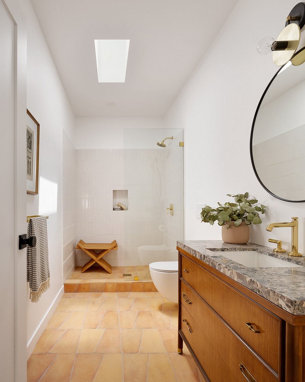 Bright, airy bathroom with wooden vanity, marble countertop, and tiled flooring.