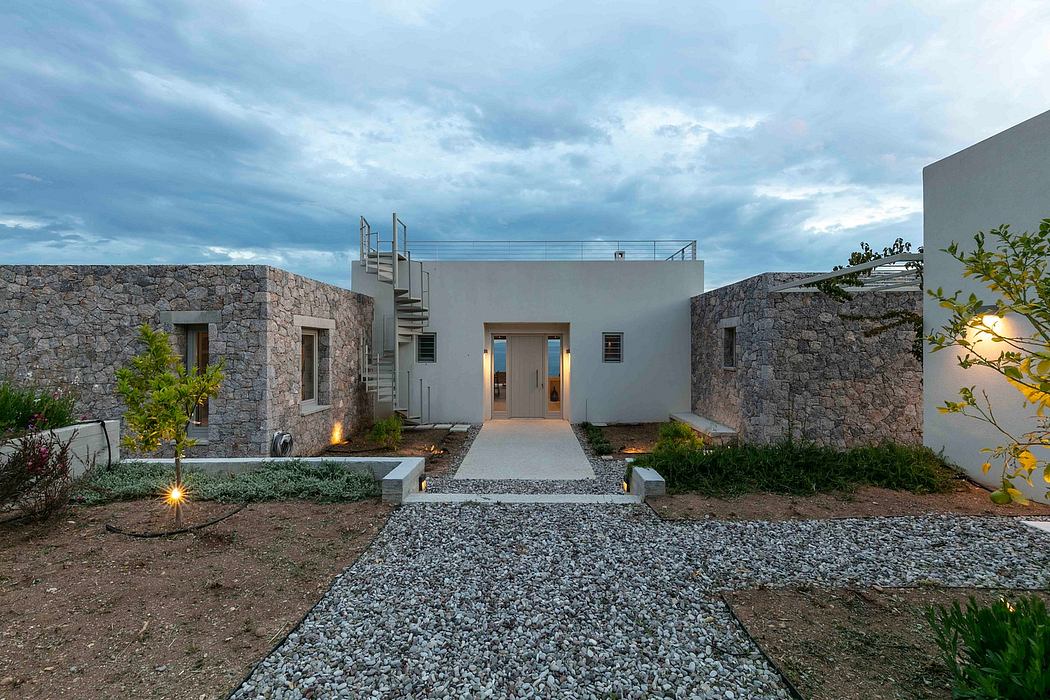A modern, minimalist home with a stone exterior, sleek staircase, and well-lit entrance.