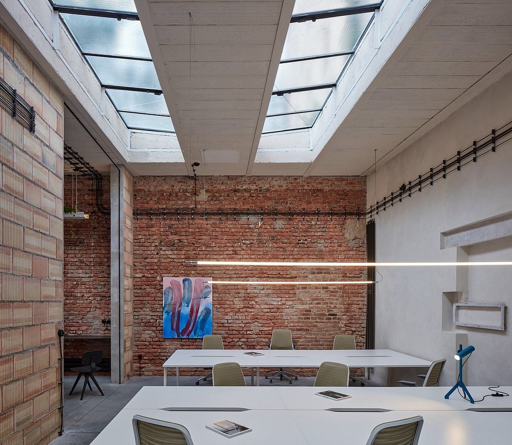 Bright, modern office space with brick walls, glass ceiling, and clean white furniture.