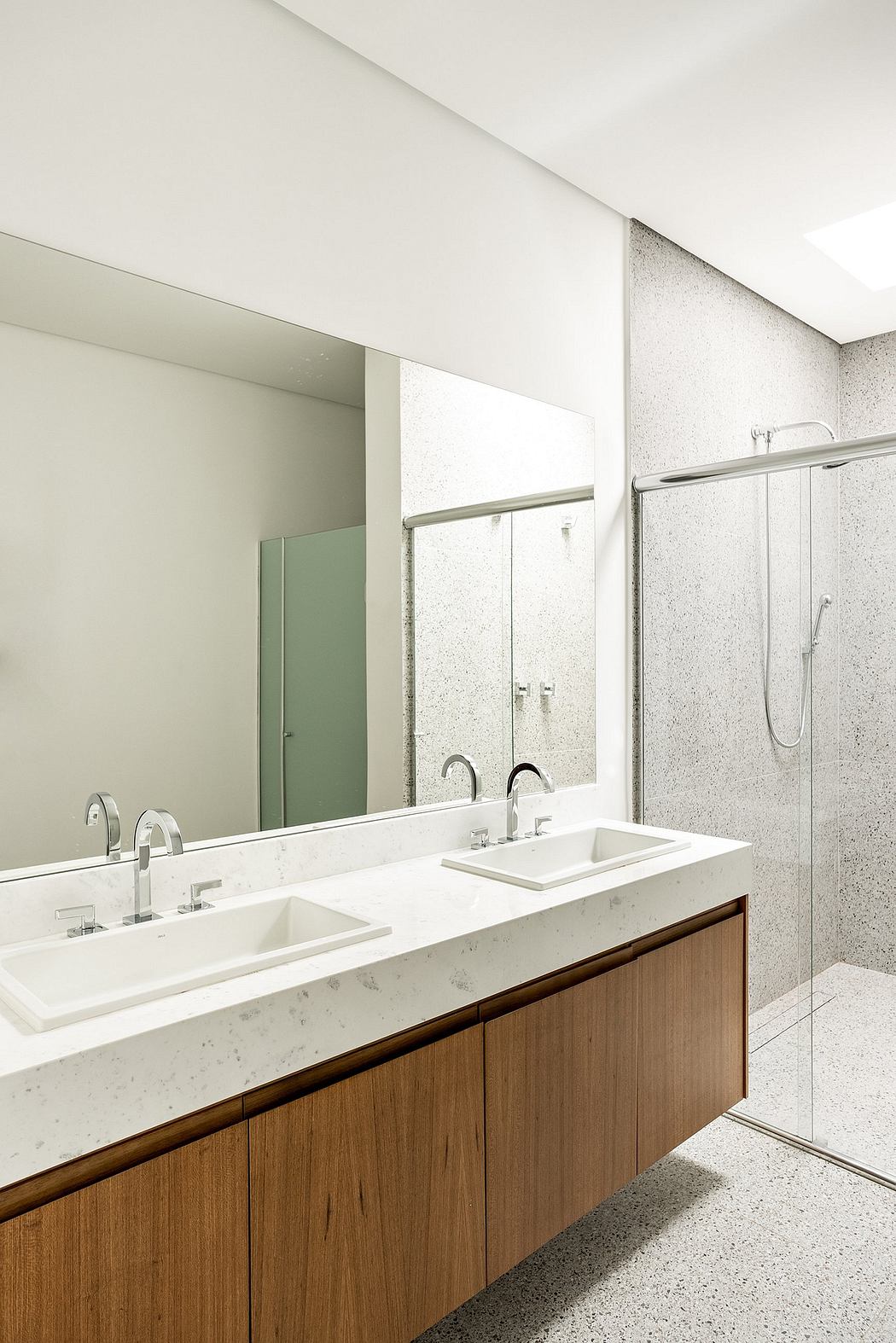 Minimalist bathroom with white marble countertop, wooden vanity, and glass shower enclosure.