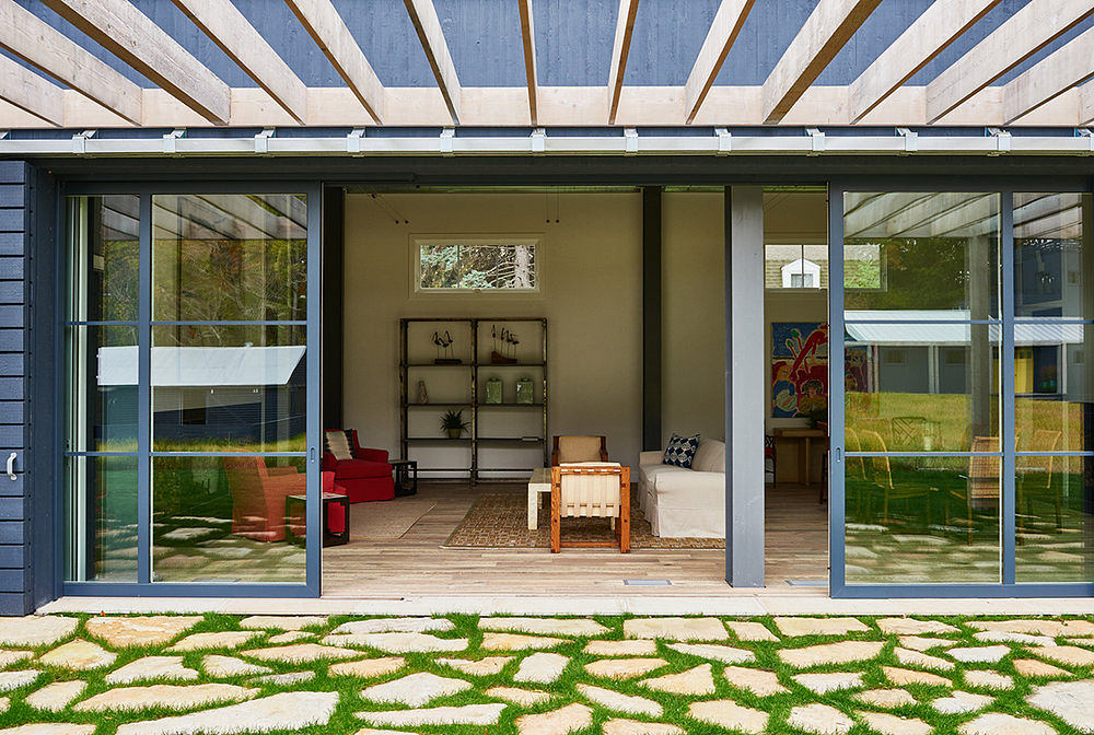 Modern glass-walled patio with rustic wood accents, stone paving, and shelving display.