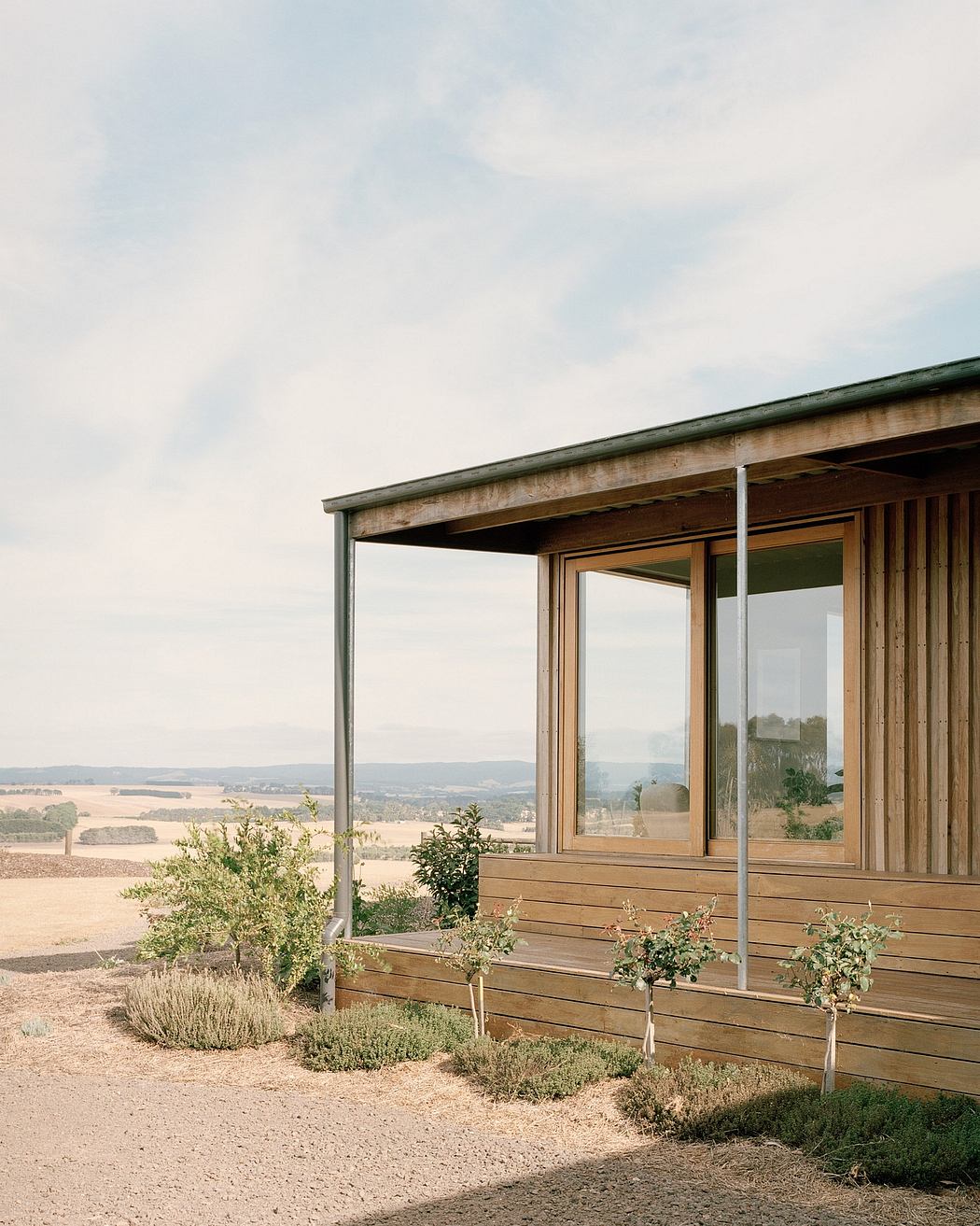 Rustic wooden cabin with large windows overlooking a scenic countryside landscape.