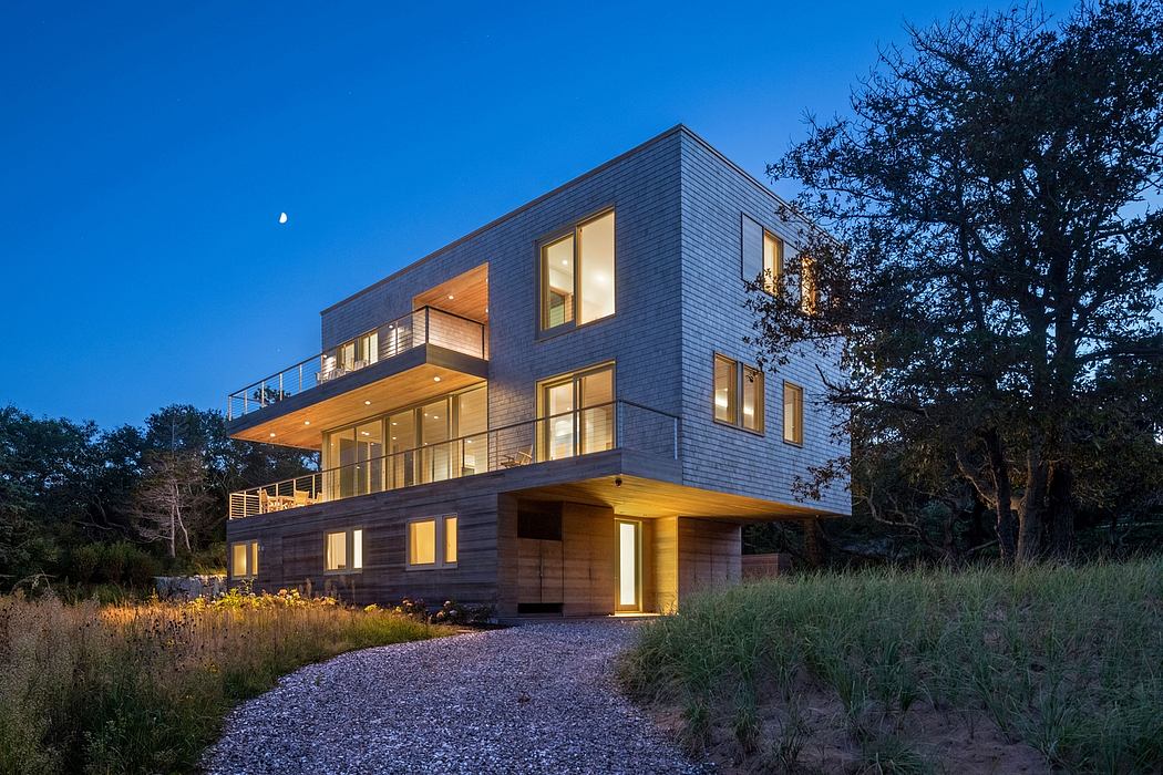Contemporary three-story home with wooden and glass exterior, balconies, and surrounded by vegetation.