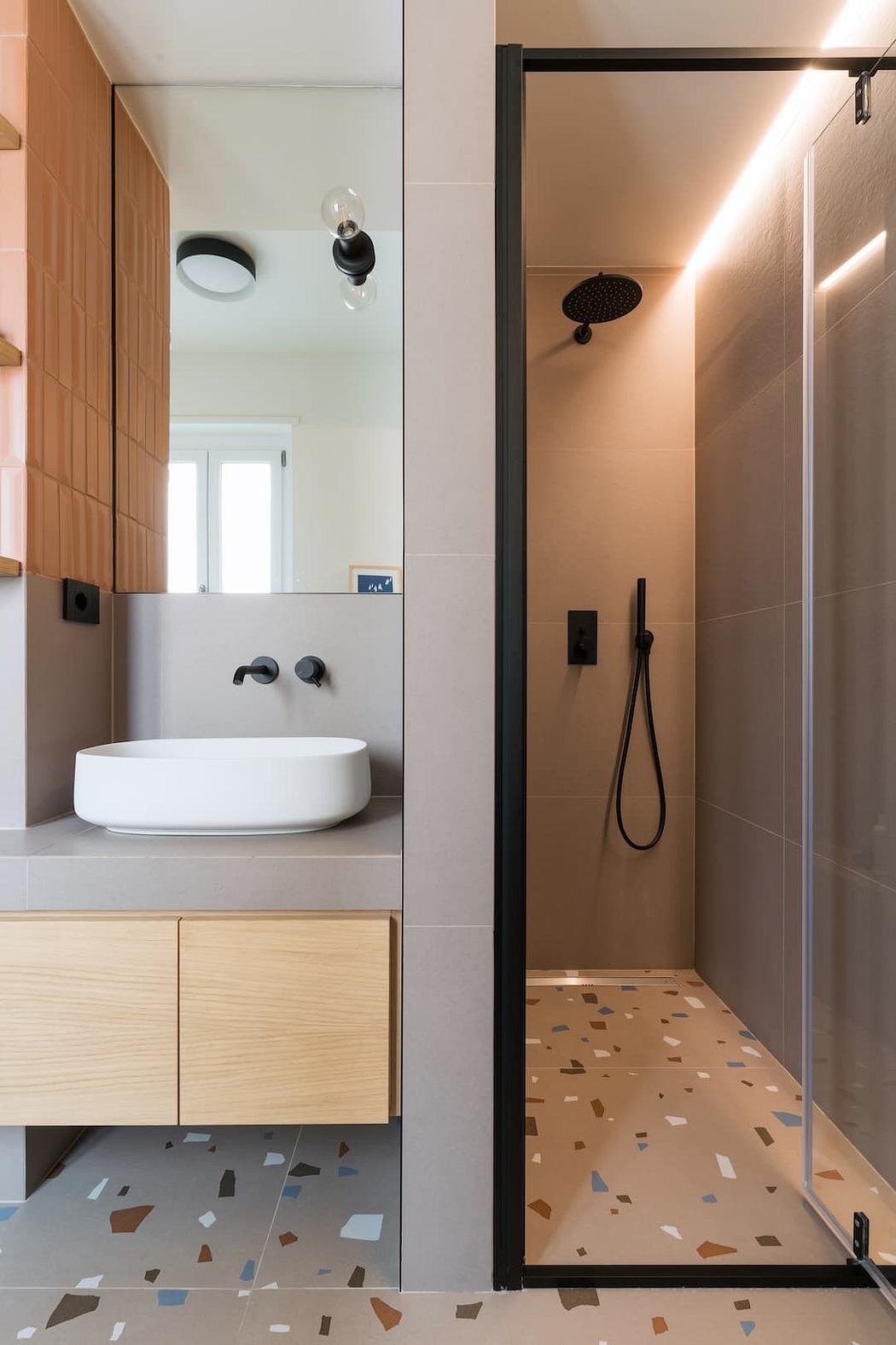 A modern bathroom with a sleek vanity, vessel sink, and a terrazzo-tiled shower stall.