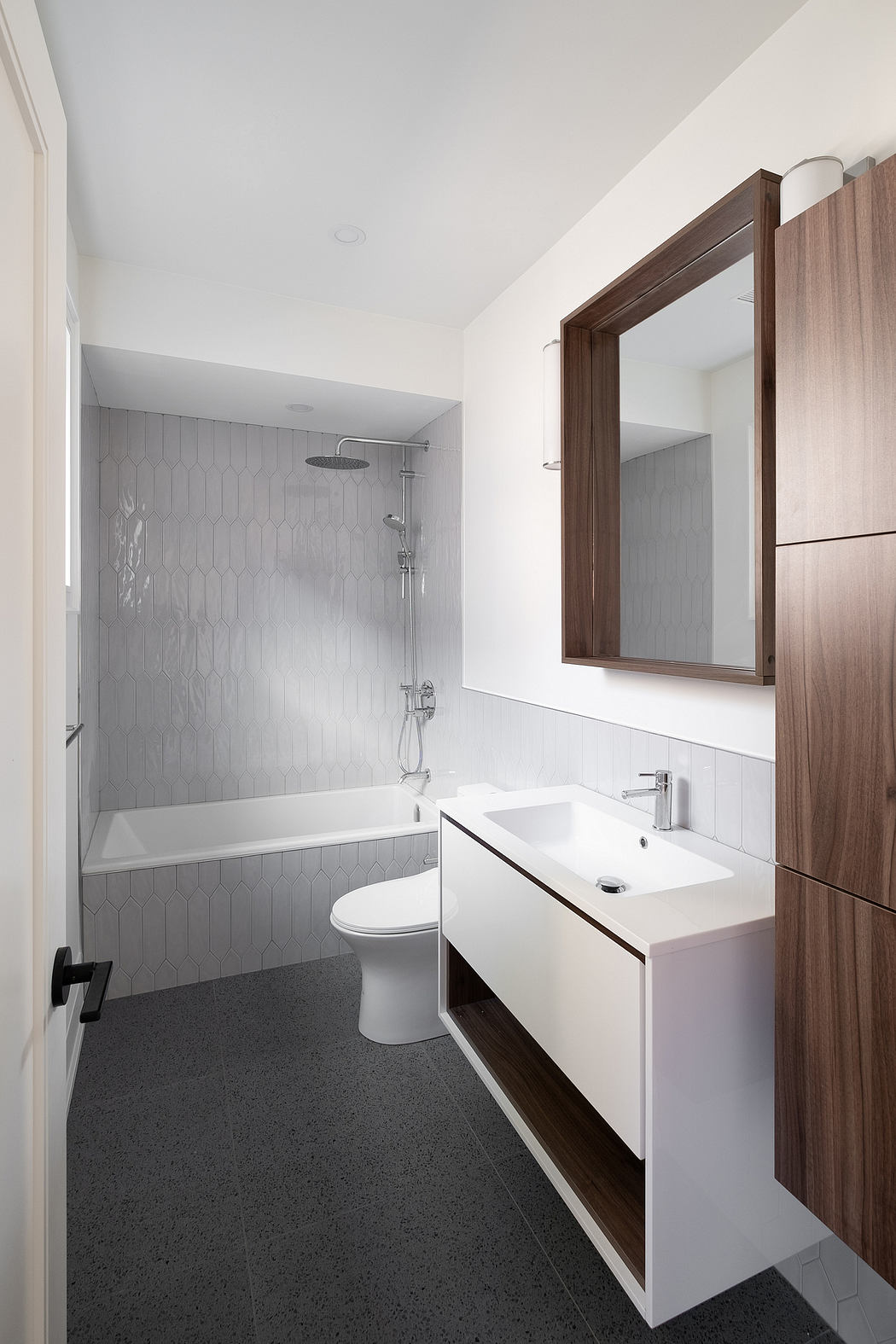 Sleek bathroom with hexagonal gray tiles, wooden vanity, and recessed mirror.