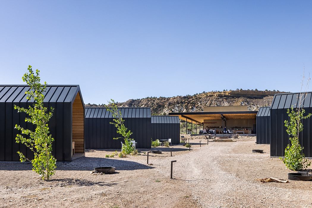 Modern cabins with black metal roofs and wood exteriors set against a desert landscape.