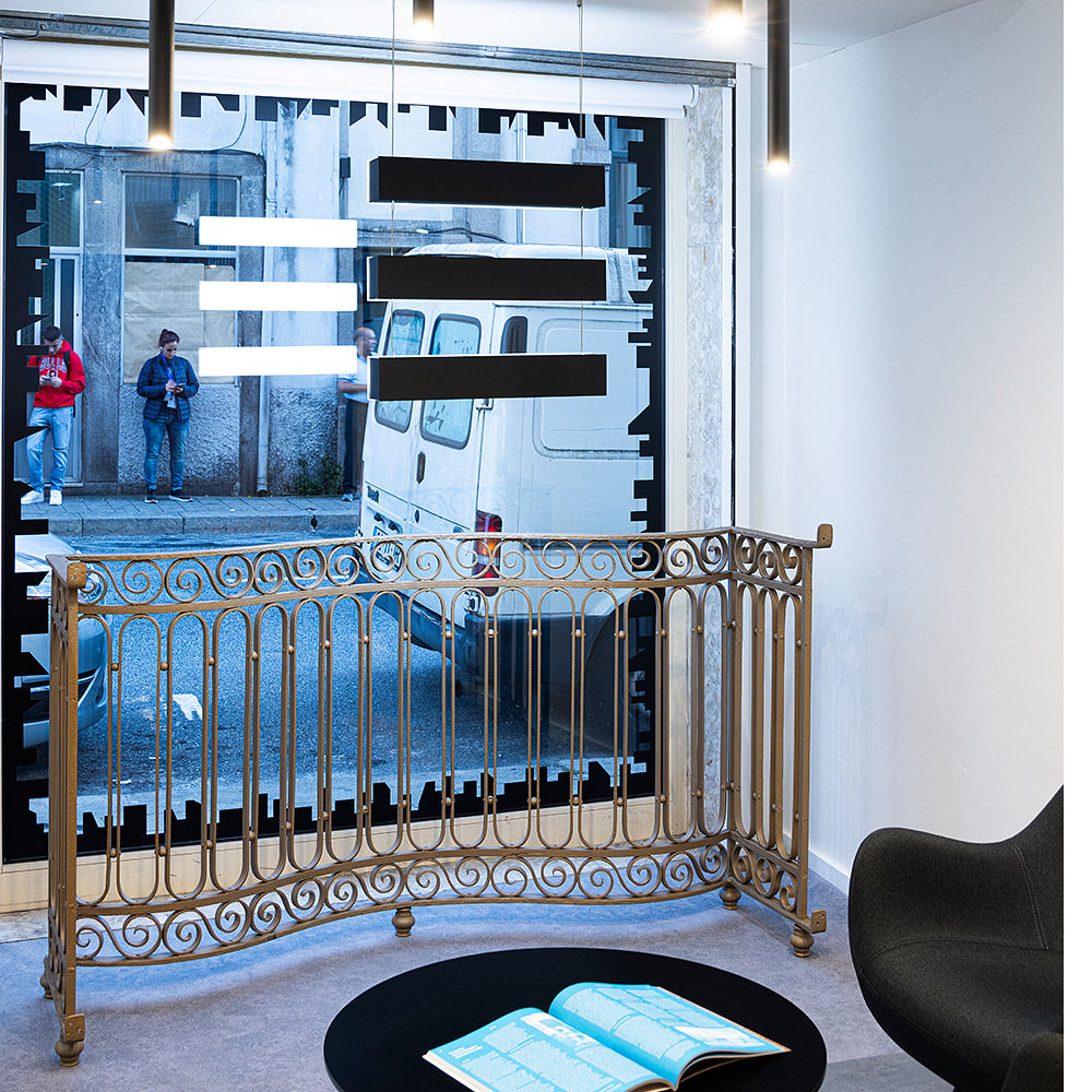 Ornate metalwork balcony, minimalist decor, and a glimpse of the urban landscape outside.