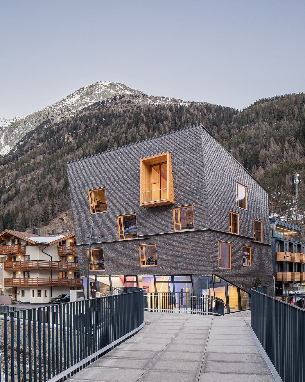 A modern mountain lodge with distinctive slanted windows and wooden accents nestled in a snowy landscape.
