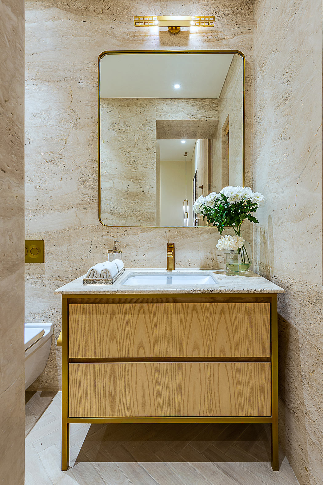 A modern bathroom with a sleek wooden vanity, a large mirror, and gold accents.