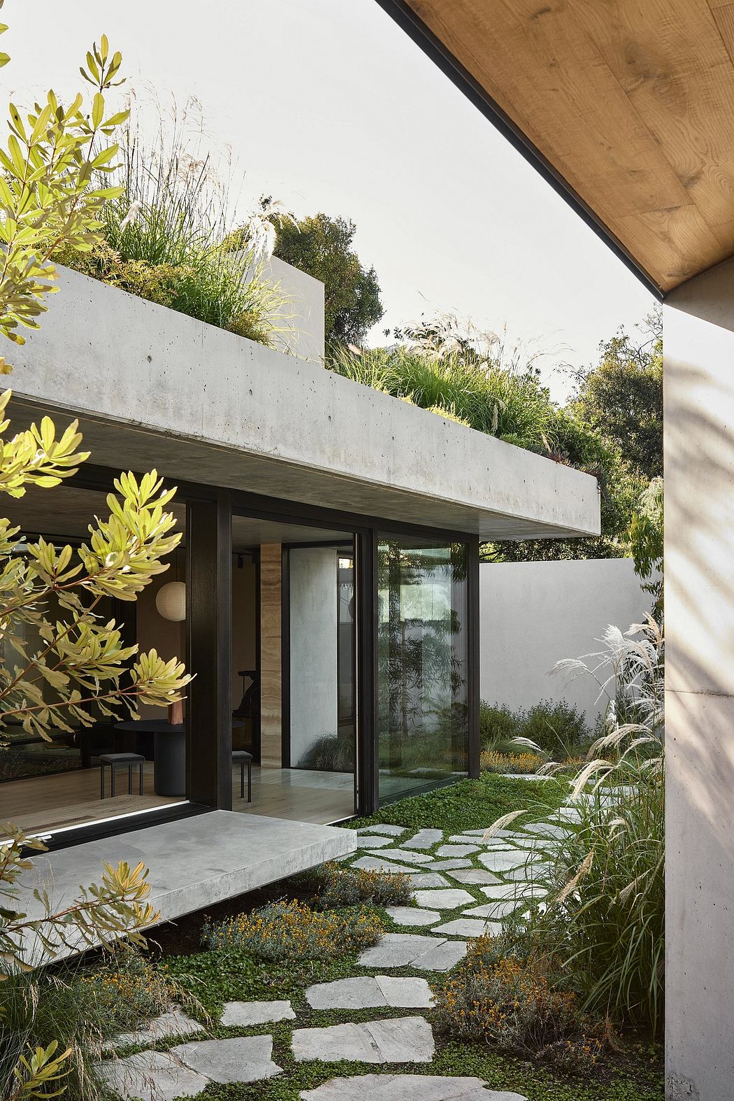 A contemporary house featuring a concrete exterior, glass panels, and a lush green-roof garden.