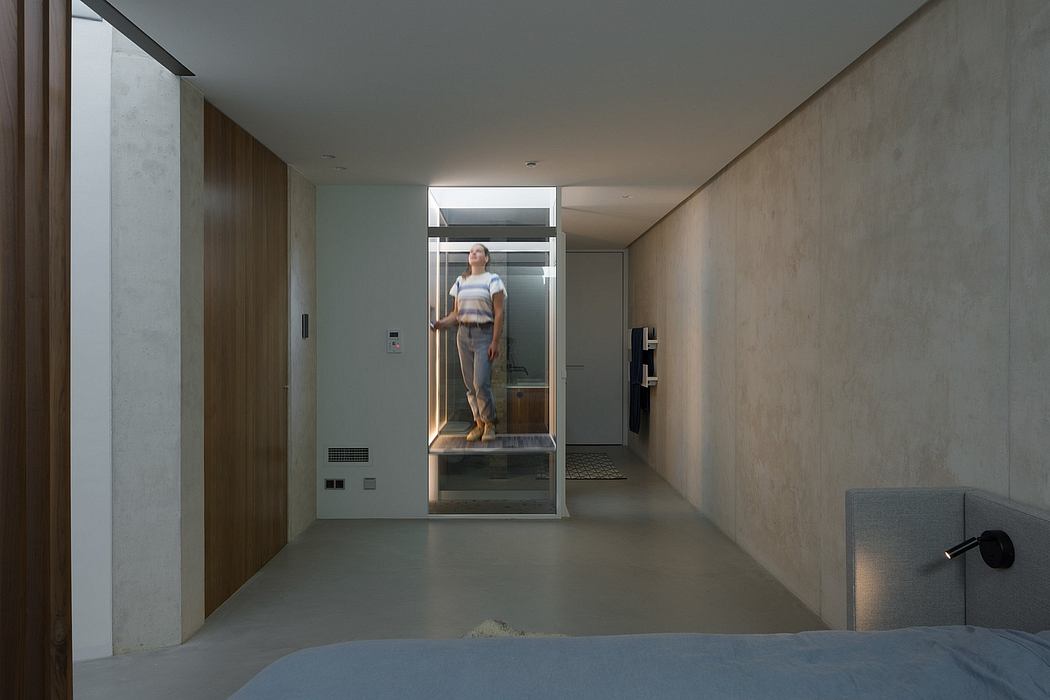 A modern, minimalist hallway with a glass-enclosed staircase leading to the upper level.