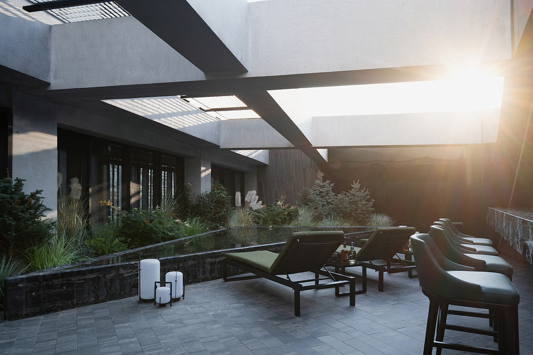An open-air terrace with sleek modern furniture, greenery, and dramatic lighting. Architectural features dominate.
