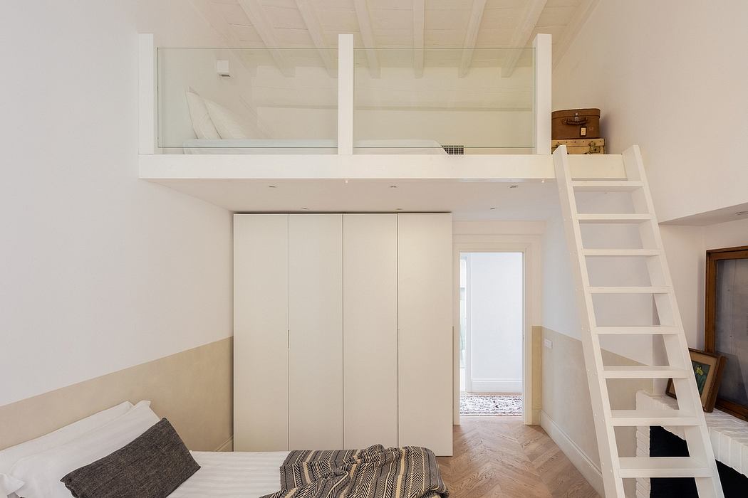 Minimalist bedroom with built-in white wardrobe, loft bed, and wooden floor.