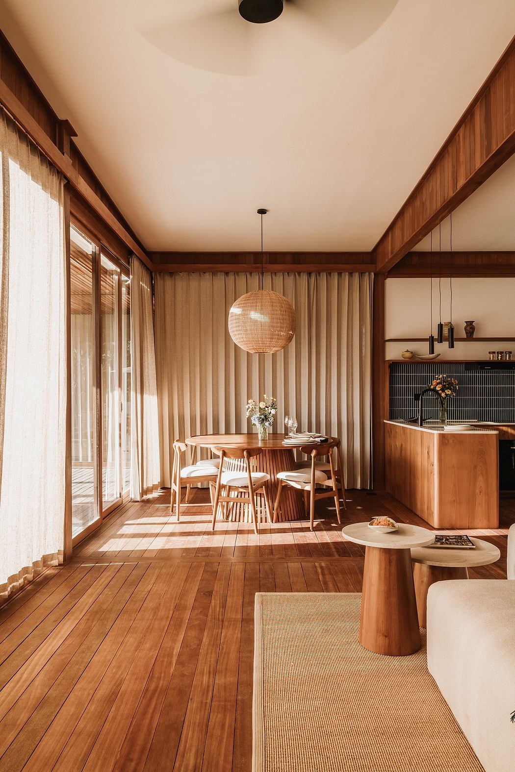 A cozy, wood-paneled dining room with a circular pendant light and minimalist furnishings.