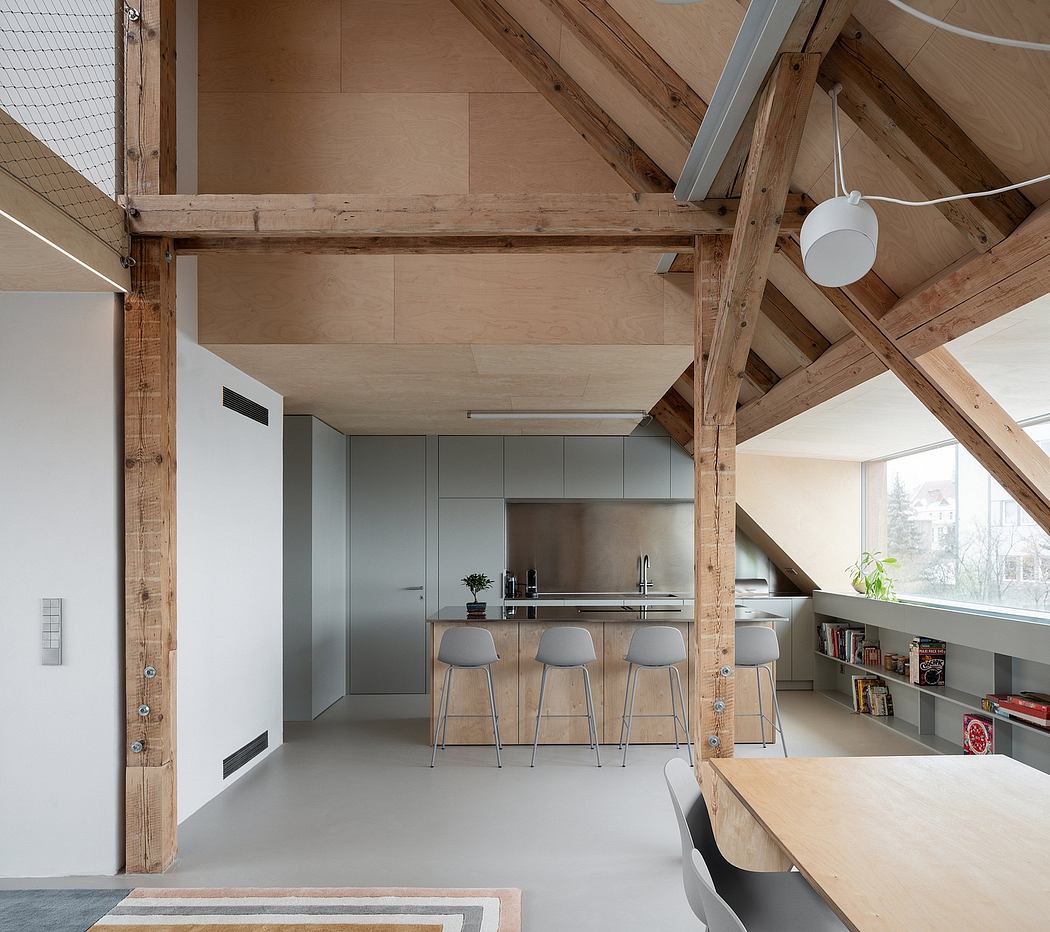 An open-concept loft with exposed wooden beams, modern kitchen, and built-in bookshelves.