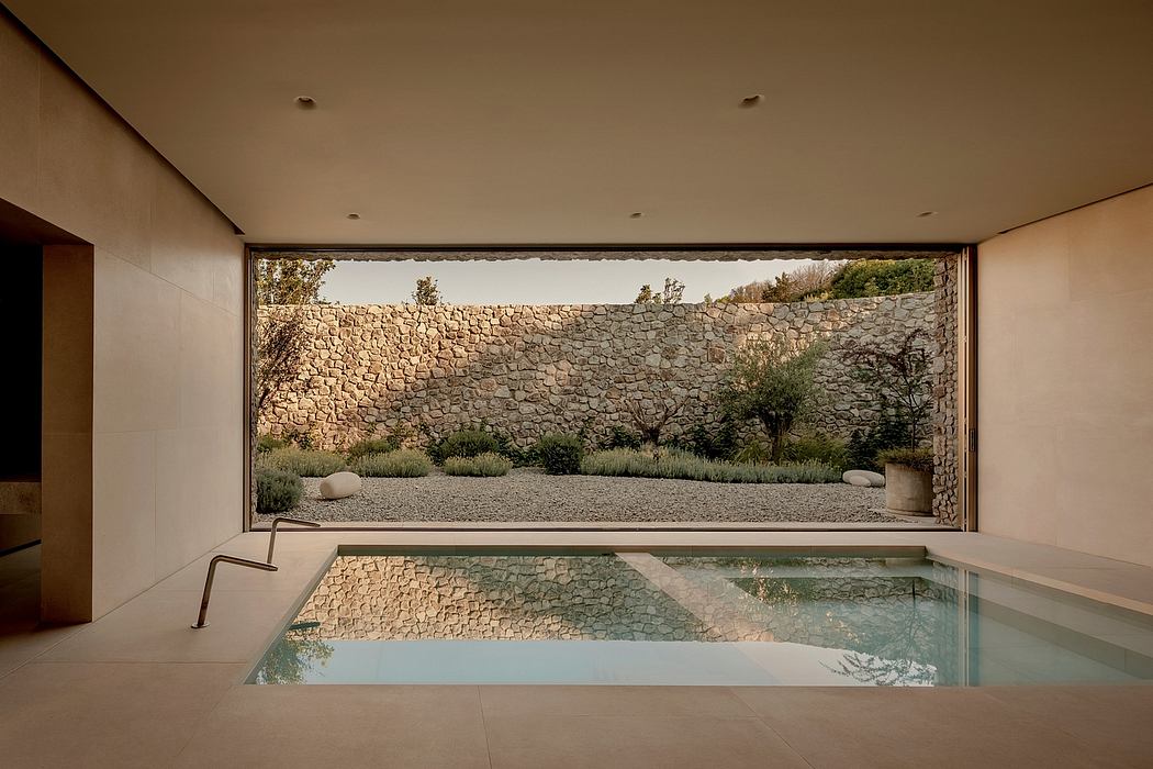 Tranquil indoor pool surrounded by stone walls and lush greenery, showcasing minimalist design.