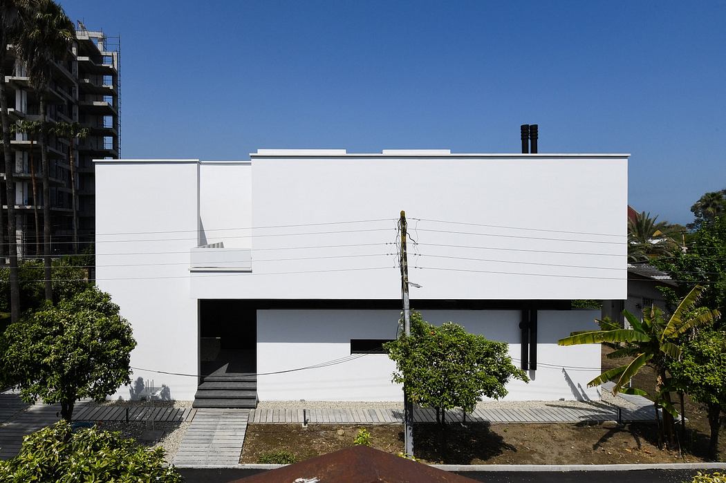 Modern white building with clean, geometric lines and minimal landscaping surrounding it.