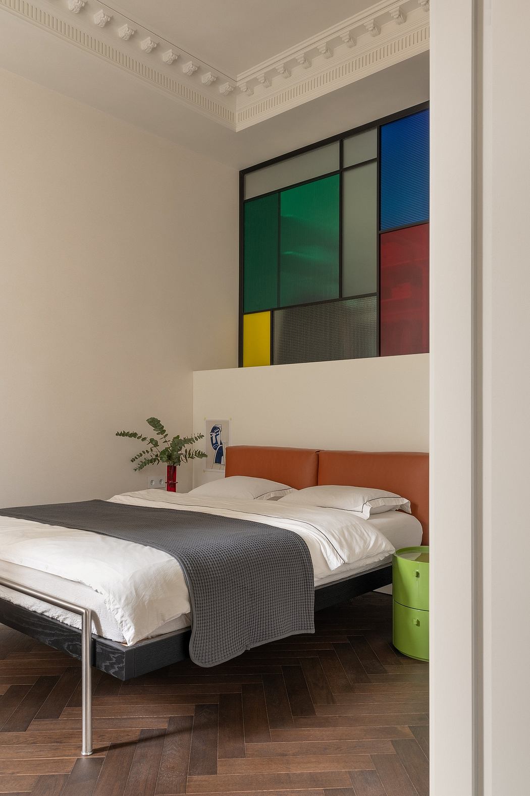 Elegant bedroom with vibrant Mondrian-inspired wall panels, plush orange sofa, and wooden flooring.