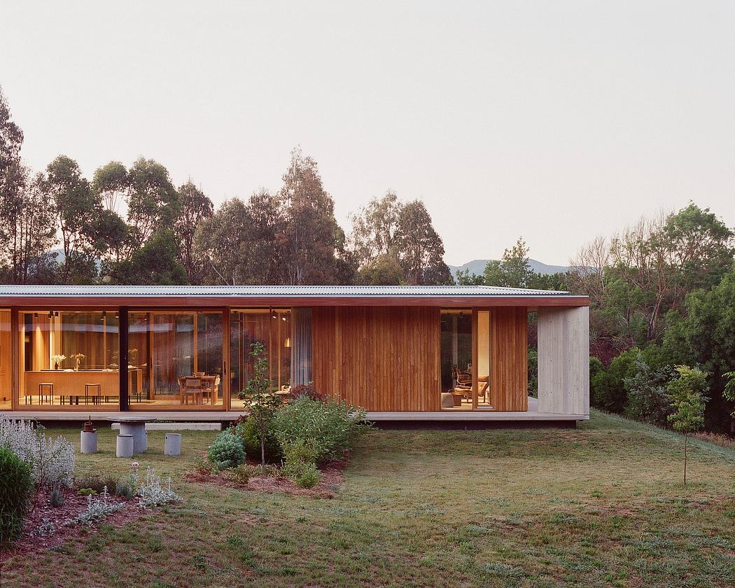 A modern, single-story cabin with wood and glass elements, surrounded by lush greenery.