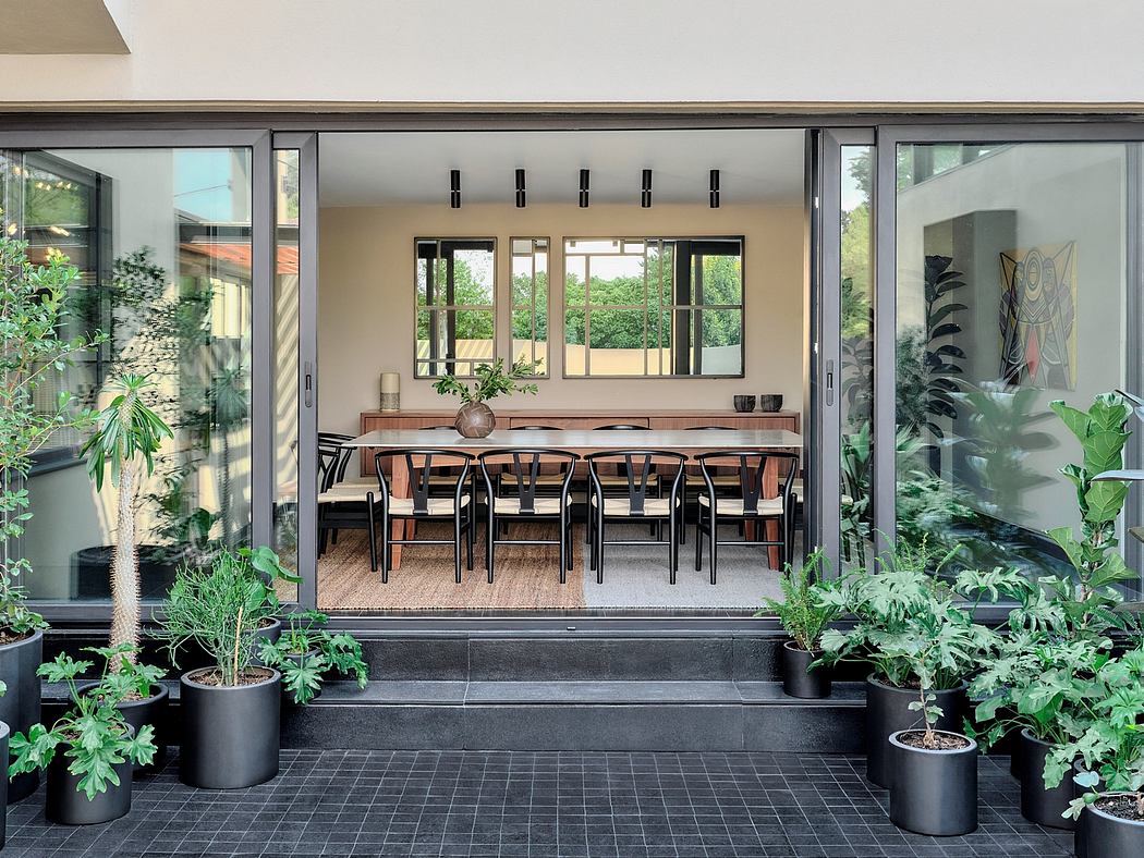 Stylish modern dining area surrounded by lush greenery and large glass windows.