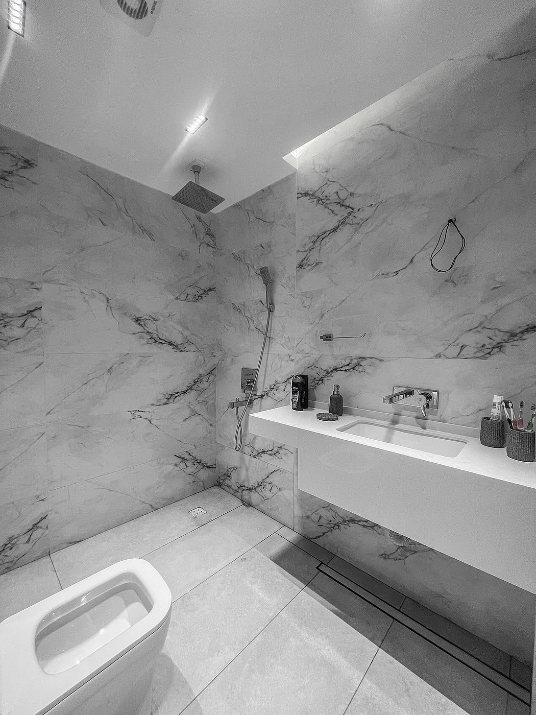 A modern bathroom with sleek marble walls, a rain shower, and minimalist vanity.