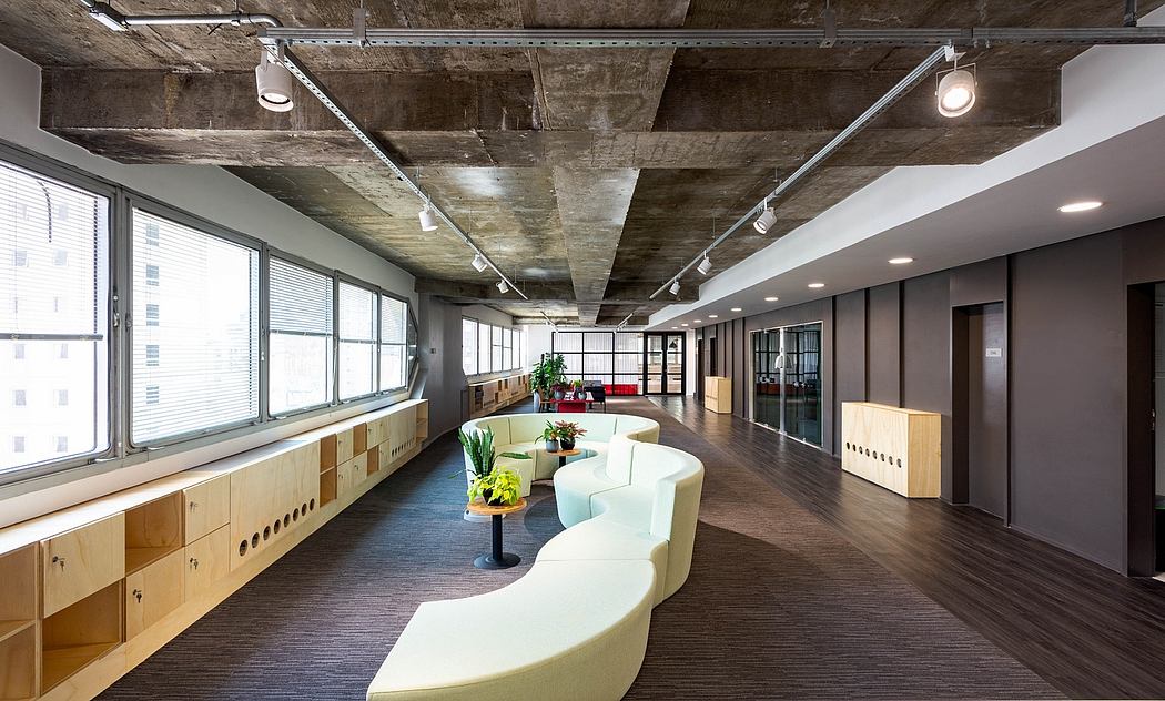 Expansive open-concept space with exposed concrete ceiling, track lighting, and modular furniture.