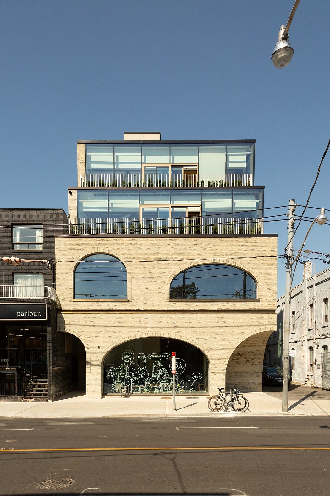 Striking modern building with arched windows, balconies, and street-level storefront.