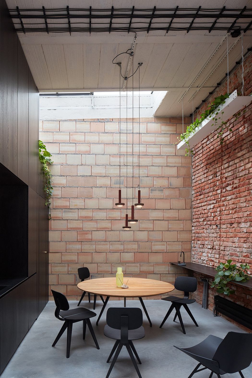 A modern interior space with exposed brick walls, industrial lighting, and a rustic wooden table.