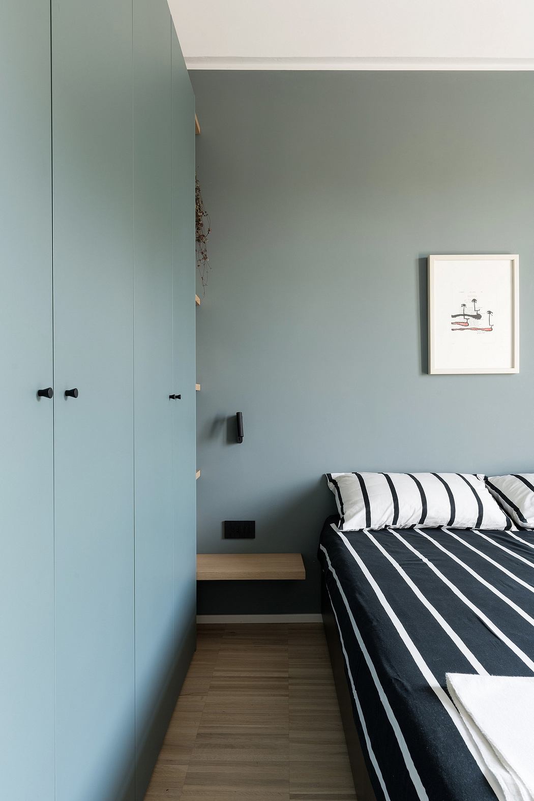 Minimalist bedroom with monochrome striped bedding, built-in closets, and wooden flooring.