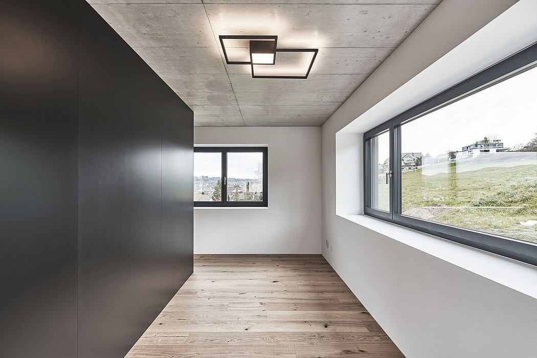 Minimalist room with concrete ceiling, wooden floor, and large window offering scenic view.